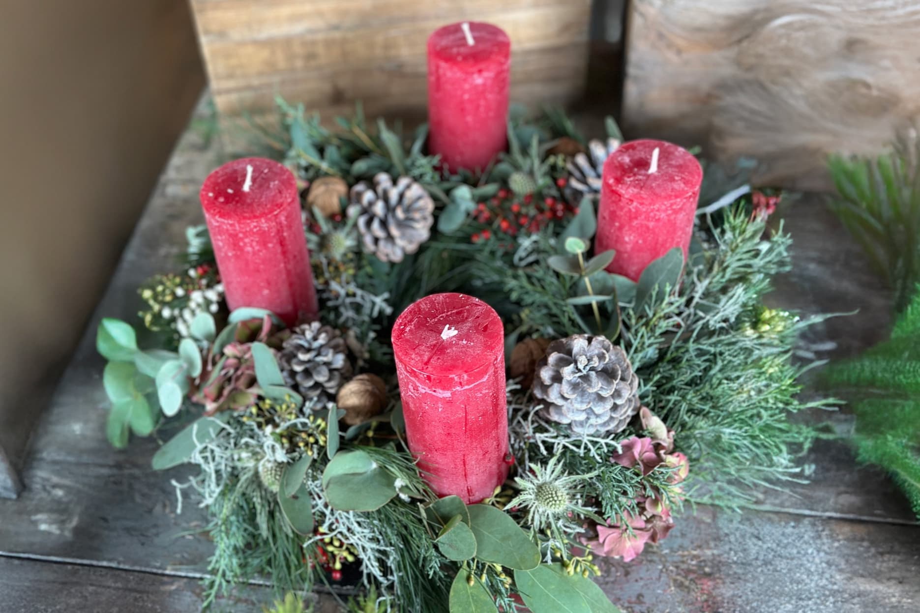 Adventskranz mit vier roten Kerzen, Zapfen und Tannengrün